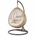Fauteuil suspendu beige en résine tressée avec support en métal, style bohème, dimensions 105x105x195 cm.